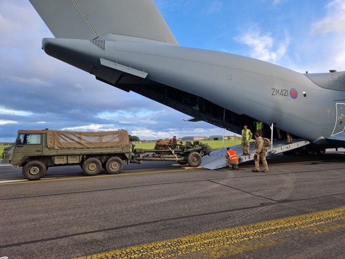 Photo - Personnel working on and adjacent to the ramp of the Atlas after within the Atlas aircraft, after the off-load a vehicle and trailer.